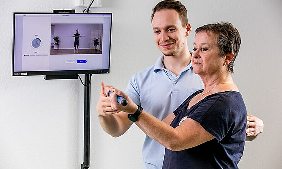 Ein Therapeut weist eine Patientin in die digitale Nachsorge ein