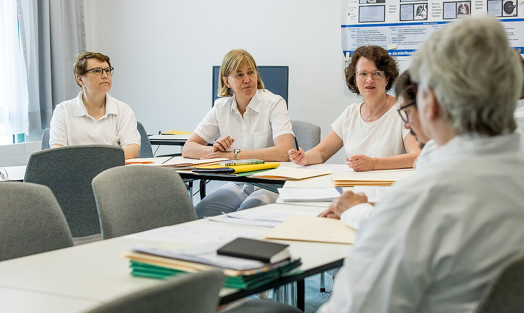 Mitarbeitendenkonferenz Eine Gruppe medizinische Angestellte sitzt gemeinsam am Tisch und spricht miteinander.