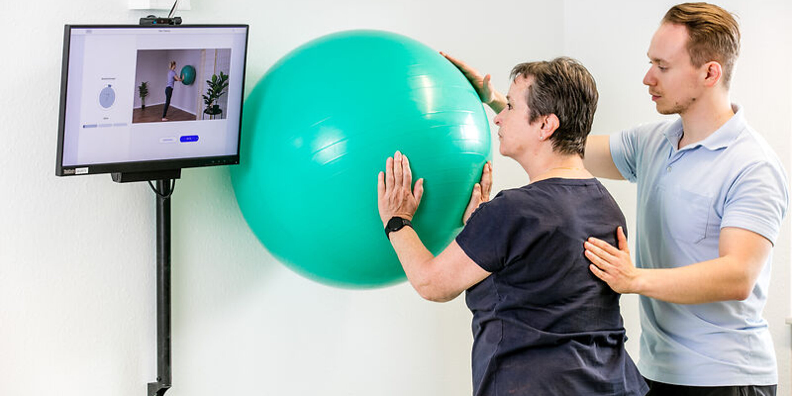 Ein Therapeut zeigt einer Patientin die digitale Nachsorge