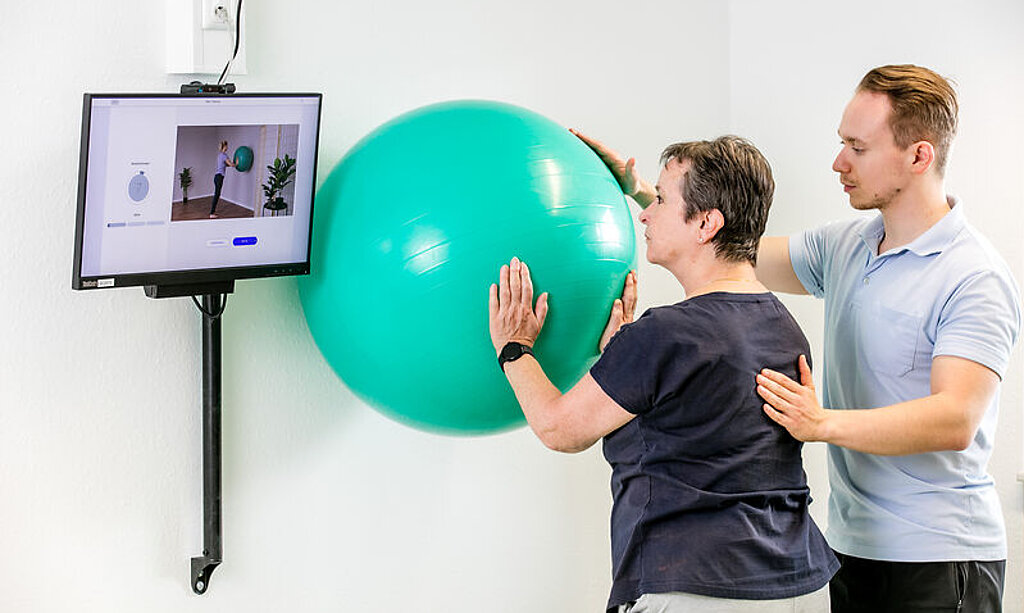 Ein Therapeut zeigt einer Patientin die digitale Nachsorge