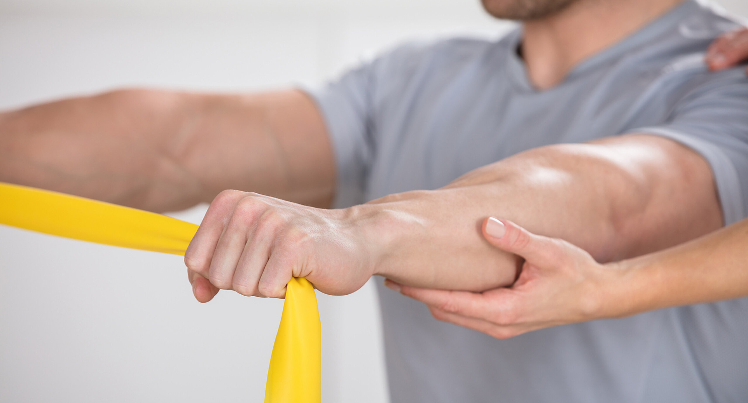 Therabandübung Ein Mann trainiert mit einem Theraband.