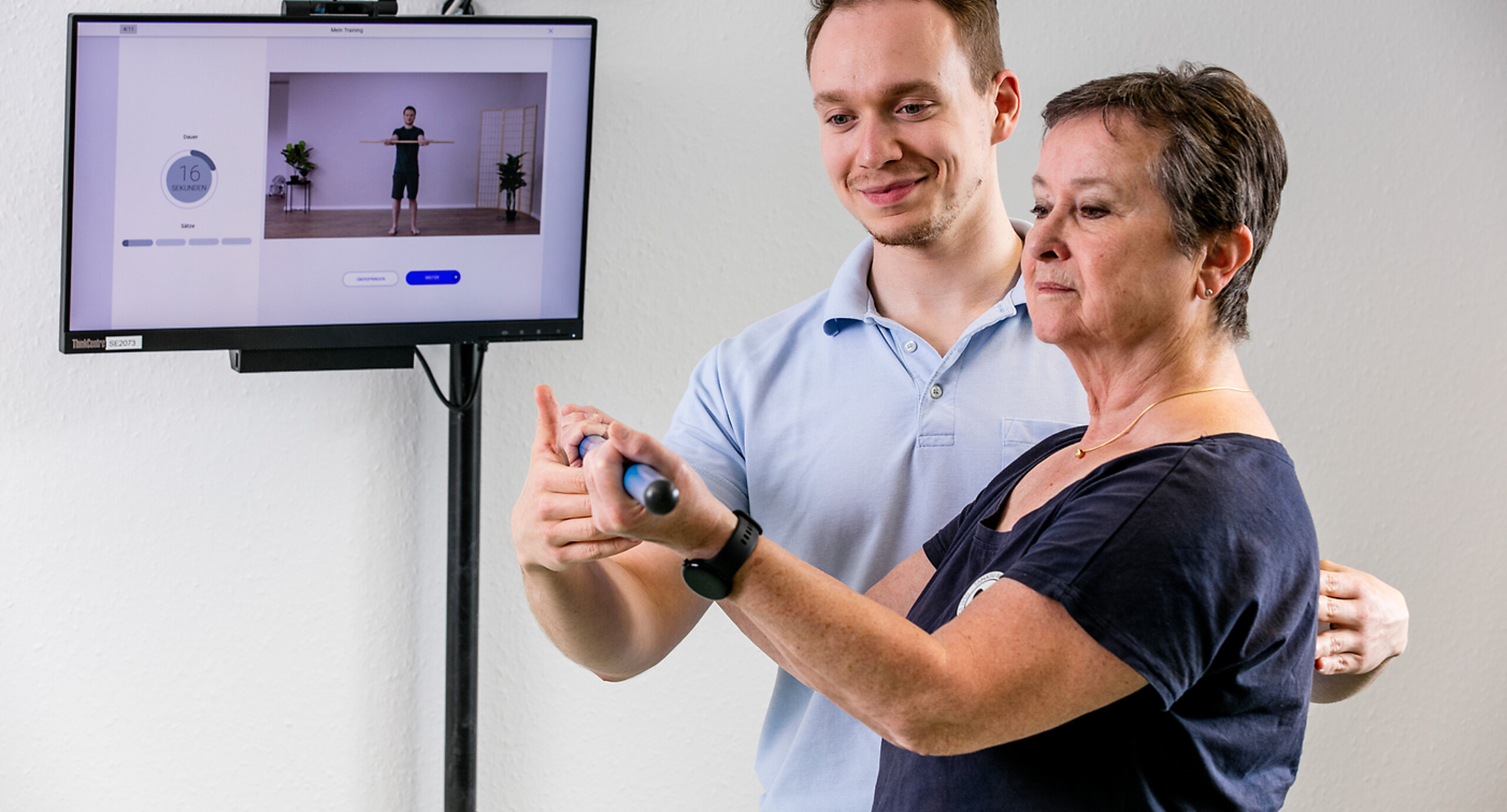 Digitale Nachsorge Ein Therapeut weist eine Patientin in die digitale Nachsorge ein